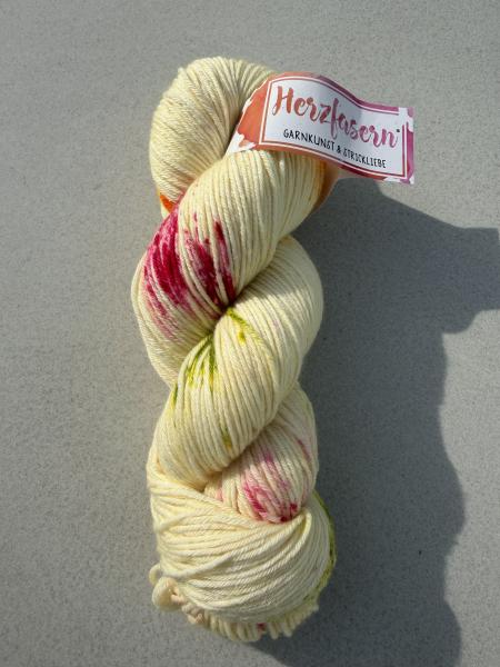Handgefärbter Wollstrang in cremigem Zitronengelb mit pinken, grünen und orangenen Sprenkeln auf Herzfasern No. 12 aus Merino Superfine.
